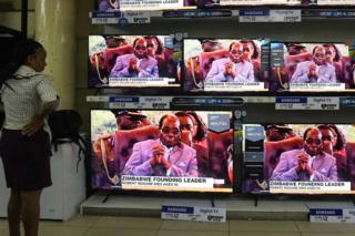 A Kenyan woman watches news with the headline on the death of former Zimbabwean president Robert Mugabe, at an electronics shop in Nairobi on September 6, 2019