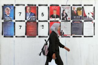 A Tunisian woman walks past posters of Tunisian presidential candidates during presidential campaign in Tunis, Tunisia, 06 September 2019