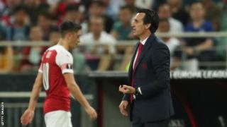 Mesut Ozil walks off the pitch past Arsenal manager Unai Emery