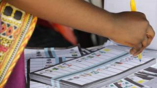 Nigeria election worker marking ballots