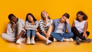 Five young adults sit on the floor in thought