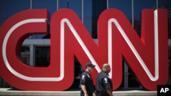 FILE - Security guards walk past the entrance to CNN headquarters in Atlanta.